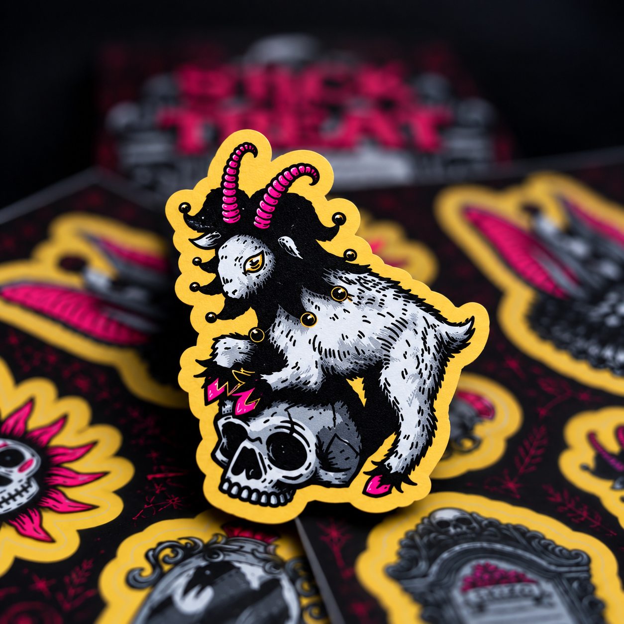 Una cabra con gorro de bufón rosa, subida a una calavera, con pegatinas al fondo.