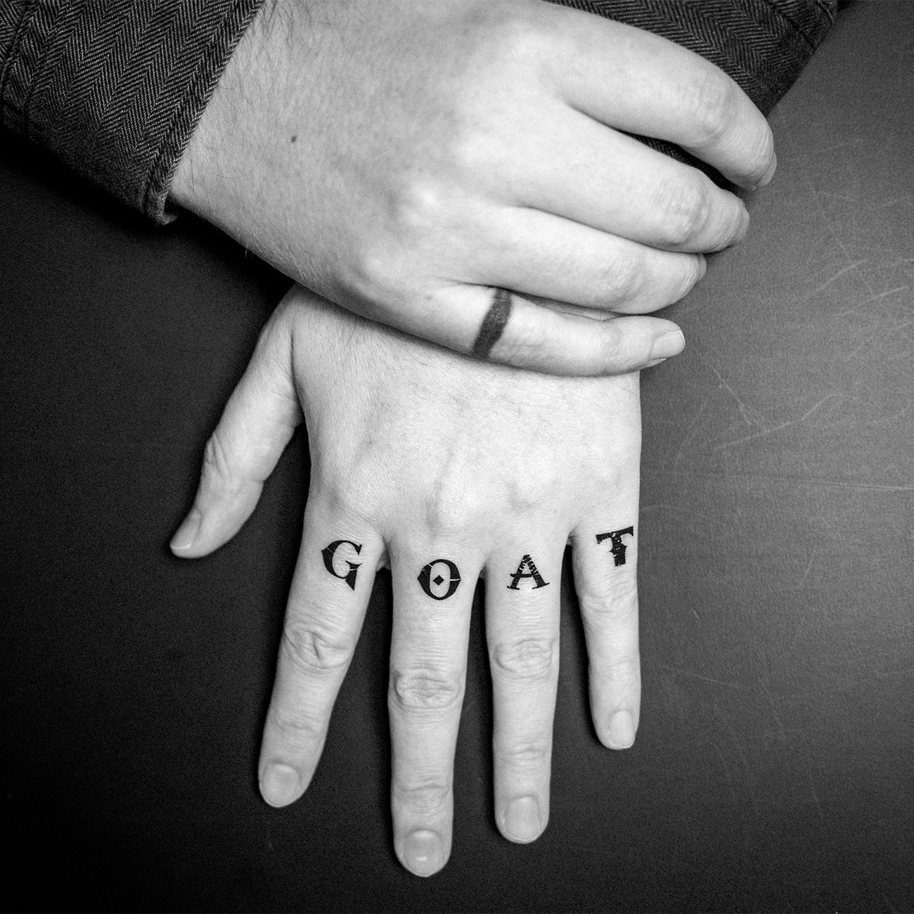 Close-up of a hand with temporary tattoos spelling “GOAT” across the fingers